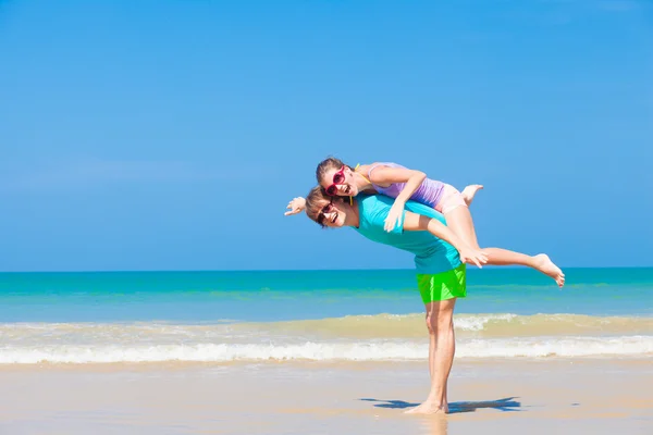 Szczęśliwa para piggybacking na wakacje na tropikalnej plaży — Zdjęcie stockowe