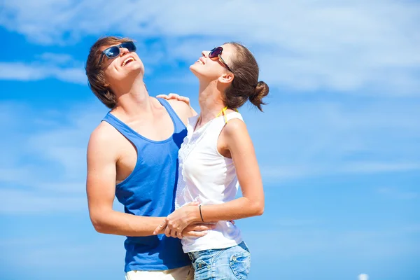 Молодая пара обнимается и смотрит на солнце на тропическом пляже — стоковое фото