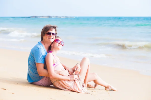 Happy young couple sitting at tropical beach — Stock Photo, Image