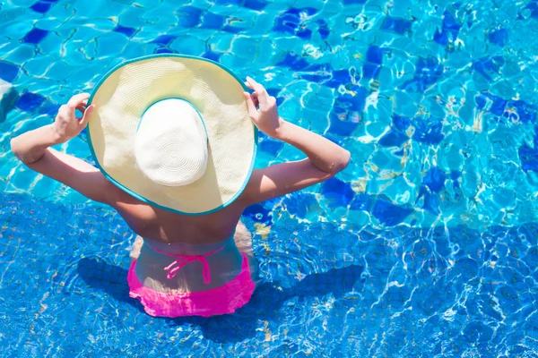 Jonge vrouw in grote hoed en roze bikini ontspannen in het zwembad — Stockfoto