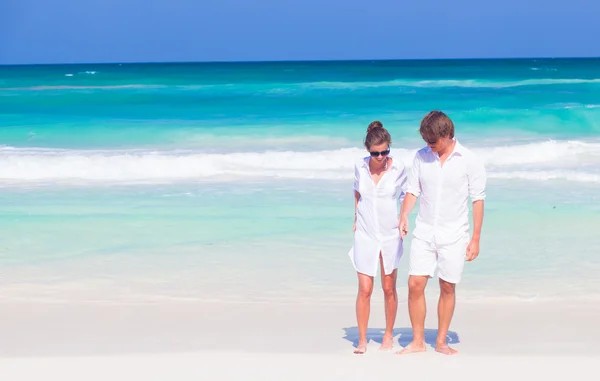Vorderansicht eines glücklichen jungen Paares in weißer Kleidung und Sonnenbrille, das Spaß am tropischen Strand hat — Stockfoto