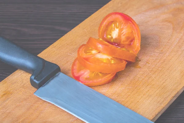 chopped tomatoes into pieces and a sharp knife on a cutting board