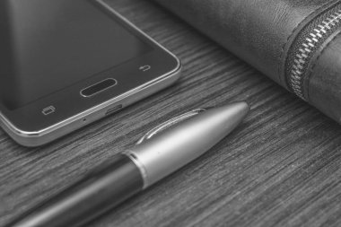 Men's accessories with a wallet, pen, smartphone on the background of the table black and white photo