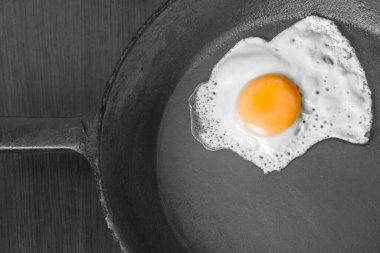 scrambled eggs with yellow yolk in a cast iron pan. Isolated on dark painted wood from above.