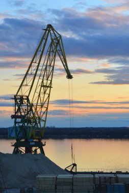 Silhouettes of tower cranes against the sunset yellow-blue-red sky.