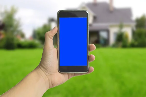 phone in hand with a blue screen on the background of a winter forest