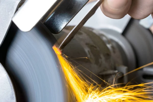 Knife sharpener in the form of a circle and a hand with a blade on the table, close-up