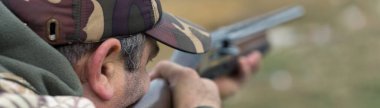 Atış poligonunda kamuflajlı bir avcı silahı ayarlıyor. Bir adam hedeflere ateş eder..