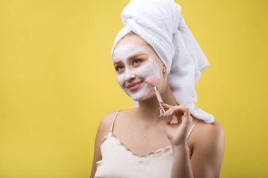Yüzünde beyaz havluyla kozmetik maske takan bir kız..