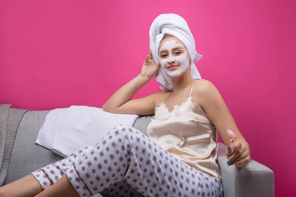 Gadis Dengan Topeng Kosmetik Wajahnya Dengan Handuk Putih Duduk Sofa — Stok Foto