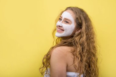 Yüzünde beyaz havluyla kozmetik maske takan bir kız..