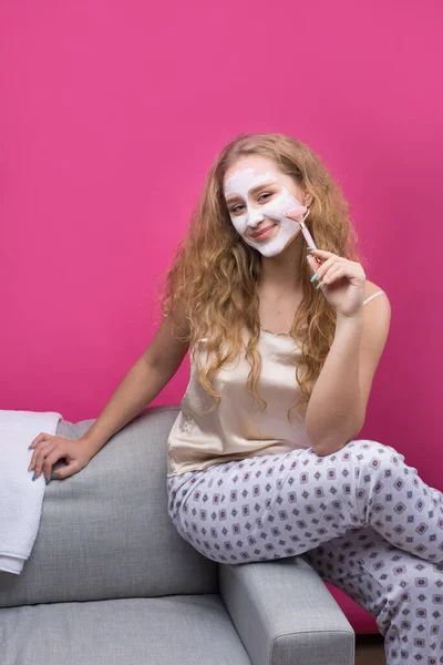 Uma Menina Com Uma Máscara Cosmética Rosto Senta Sofá — Fotografia de Stock