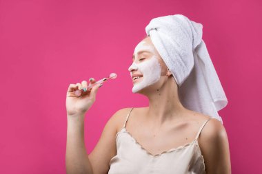 Yüzünde beyaz havluyla kozmetik maske takan bir kız..