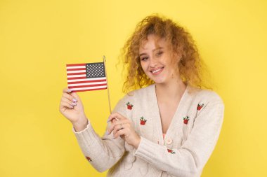Yüzünde bir gülümseme olan genç mutlu bir kız ellerinde bir Amerikan bayrağı tutuyor. Vatanseverliğin ve özgürlüğün sembolü..