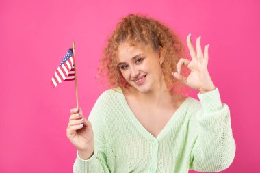 Yüzünde bir gülümseme olan genç mutlu bir kız ellerinde bir Amerikan bayrağı tutuyor. Vatanseverliğin ve özgürlüğün sembolü..