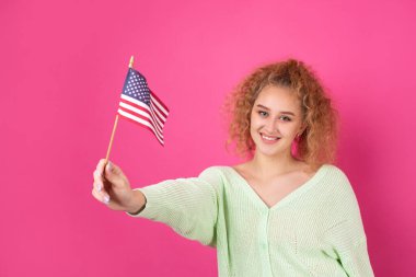 Yüzünde bir gülümseme olan genç mutlu bir kız ellerinde bir Amerikan bayrağı tutuyor. Vatanseverliğin ve özgürlüğün sembolü..