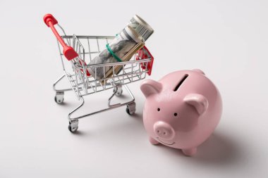 Amerikan banknotlarıyla pembe domuz kumbarası. Beyaz arka planda 100 dolarlık banknotlar..