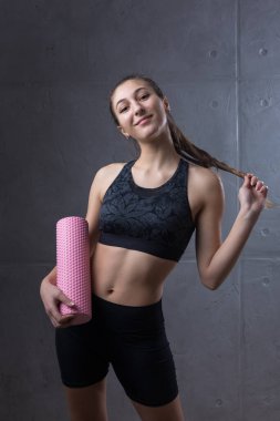 Şık bir apartmanın içinde beton bir duvara dayanmış ince, atletik bir genç kızın portresi.