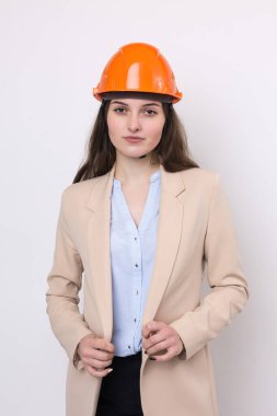 Takım elbiseli bir kız mimar ve turuncu bir miğfer beyaz arka planda duruyor..