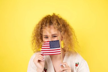 Yüzünde bir gülümseme olan genç mutlu bir kız ellerinde bir Amerikan bayrağı tutuyor. Vatanseverliğin ve özgürlüğün sembolü..