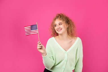 Yüzünde bir gülümseme olan genç mutlu bir kız ellerinde bir Amerikan bayrağı tutuyor. Vatanseverliğin ve özgürlüğün sembolü..