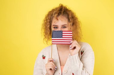 Yüzünde bir gülümseme olan genç mutlu bir kız ellerinde bir Amerikan bayrağı tutuyor. Vatanseverliğin ve özgürlüğün sembolü..