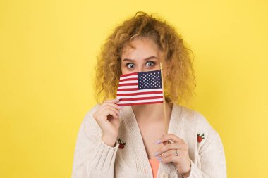 Yüzünde bir gülümseme olan genç mutlu bir kız ellerinde bir Amerikan bayrağı tutuyor. Vatanseverliğin ve özgürlüğün sembolü..
