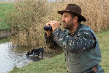 Avlanırken av sırasında av hayvanı ya da av hayvanı arayan kamuflajlı bir avcı. Sonbahar av sezonu.