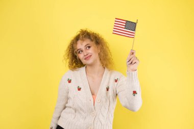 Yüzünde bir gülümseme olan genç mutlu bir kız ellerinde bir Amerikan bayrağı tutuyor. Vatanseverliğin ve özgürlüğün sembolü..