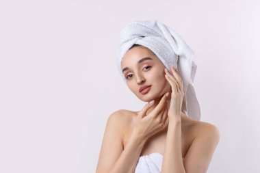 Kalın kaşlı güzel bir kız, beyaz arka planda mükemmel bir ten, kafasında havlu, güzel bir fotoğraf..