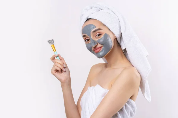 Een Vrouw Met Een Grijze Klei Cosmetische Masker Een Witte — Stockfoto