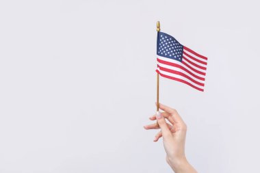 Güzel bir kadın eli beyaz bir arka planda Amerikan bayrağı taşıyor..