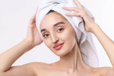 Kalın kaşlı güzel bir kız, beyaz arka planda mükemmel bir ten, kafasında havlu, güzel bir fotoğraf..