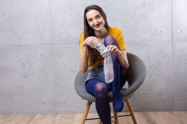 Sıradan giyinmiş zengin bir kadının fotoğrafı. Elinde beton bir arka planda izole edilmiş bir para yelpazesi var.