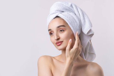 Kalın kaşlı güzel bir kız, beyaz arka planda mükemmel bir ten, kafasında havlu, güzel bir fotoğraf..