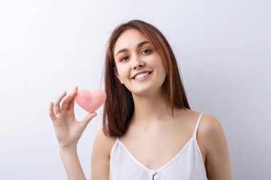 Temiz ciltli, doğal makyajlı ve gri arka planda beyaz dişli güzel bir kadın.