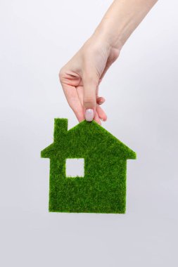Kadın eli, yakın plan bir yeşil evin modelini tutuyor. Geleceğin ekolojik gayrimenkullerinin satışı.
