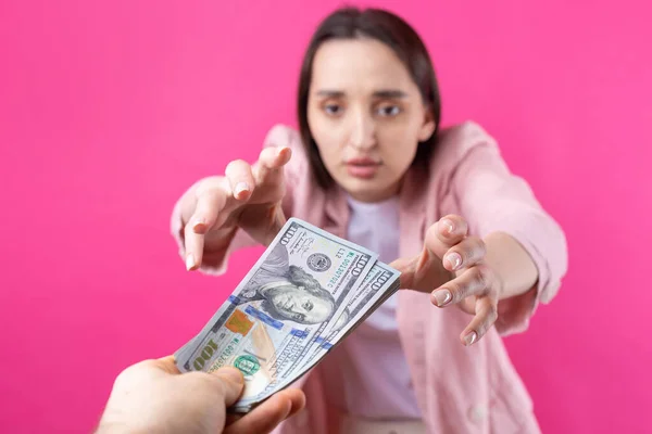 一个穿着粉色夹克的女人在红色背景下收到了美元贿赂 — 图库照片