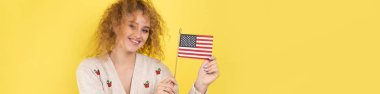 Yüzünde bir gülümseme olan genç mutlu bir kız ellerinde bir Amerikan bayrağı tutuyor. Vatanseverliğin ve özgürlüğün sembolü..