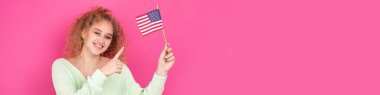 Yüzünde bir gülümseme olan genç mutlu bir kız ellerinde bir Amerikan bayrağı tutuyor. Vatanseverliğin ve özgürlüğün sembolü..