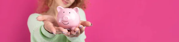 一个可爱的小女孩 一头卷曲的红头发 手里拿着一只小猪 一只粉色的小猪 财富和货币安全的概念 — 图库照片