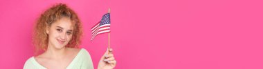 Yüzünde bir gülümseme olan genç mutlu bir kız ellerinde bir Amerikan bayrağı tutuyor. Vatanseverliğin ve özgürlüğün sembolü..