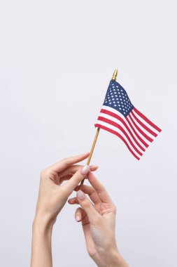Güzel bir kadın eli beyaz bir arka planda Amerikan bayrağı taşıyor..