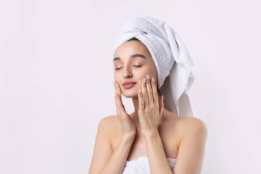 Kalın kaşlı güzel bir kız, beyaz arka planda mükemmel bir ten, kafasında havlu, güzel bir fotoğraf..