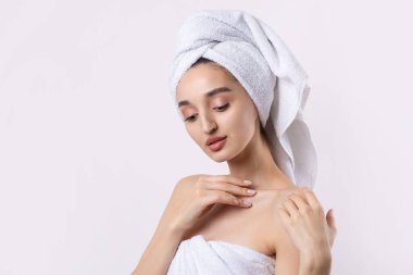 Kalın kaşlı güzel bir kız, beyaz arka planda mükemmel bir ten, kafasında havlu, güzel bir fotoğraf..