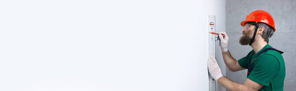 An electrician installs sockets in the apartment. A guy in an orange helmet and overalls makes electrics in the house.