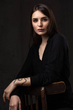 Stüdyoda uzun saçlı genç bir esmerin portresi. Koyu renkli dramatik fotoğraf.