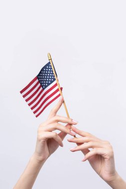 Güzel bir kadın eli beyaz bir arka planda Amerikan bayrağı taşıyor..