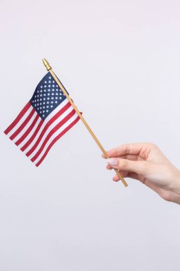 Güzel bir kadın eli beyaz bir arka planda Amerikan bayrağı taşıyor..