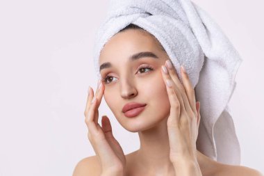 Kalın kaşlı güzel bir kız, beyaz arka planda mükemmel bir ten, kafasında havlu, güzel bir fotoğraf..